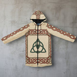 A beige hooded zip-up jacket featuring a green Celtic triquetra symbol in the center, surrounded by a border of red and green Celtic knotwork patterns, displayed flat against a white background.