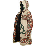 A hooded cloak featuring a cream-colored base with a detailed Celtic knot pattern in terracotta red and dark green, with a solid black lining visible along the front opening.