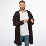 A man wearing a black hooded jacket with a red rune-like pattern 