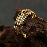 Gold ring with intricate design on a textured brown surface