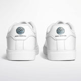 A pair of white low-top sneakers shown from the back, featuring a circular blue and silver compass emblem and the text 'VIKS VARRICKS' printed below it on a clean white background.