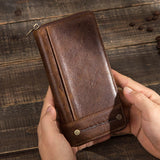Brown leather wallet held by a person on a wooden surface