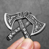 Silver axe-shaped pendant held by a hand against a gray background