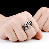 Silver knuckle ring on a person's finger with a black background