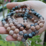 Three beaded bracelets of different colors held in a hand with a blurred green background