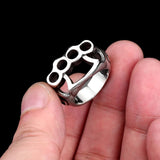 Silver knuckle duster ring held between fingers