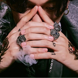 Person with intricate tattoos and multiple rings on hands, wearing a Beier branded shirt.