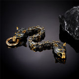 Gold and black bracelet with wolf head design on a dark reflective surface