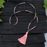 Necklace with pink tassel on a wooden surface