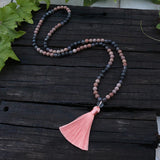 Necklace with pink tassel on a wooden surface