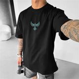Person wearing a black t-shirt with a blue raven logo, standing indoors.