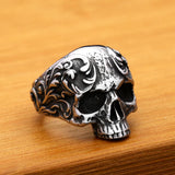Silver skull ring with intricate designs on a wooden surface