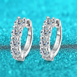 Silver hoop earrings with clear gemstones on a turquoise background, featuring the brand 'Smyoue'.