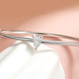 Silver bracelet with a pear-shaped diamond on a soft pink background