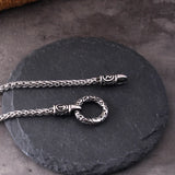 Silver necklace with intricate design on a dark stone surface