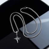 Silver chain necklace with a star pendant on a black surface