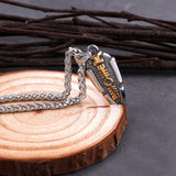Silver and gold spear pendant on a wooden block with a dark background