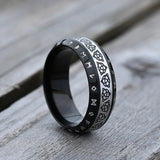 Black ring with engraved patterns on a wooden surface