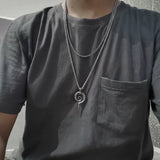 Person wearing a dark gray t-shirt with a silver spiral pendant necklace