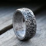 Silver ring with textured surface on a wooden background