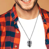 Man wearing a silver necklace with a pendant against a beige background