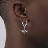 Silver Thor's hammer earring worn by a person with a neutral background