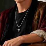Person wearing a black shirt with a silver chain necklace featuring a star pendant.