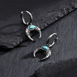 Silver earrings with turquoise stones on a dark stone surface