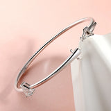 Silver bracelet with a heart-shaped gemstone on a soft pink background