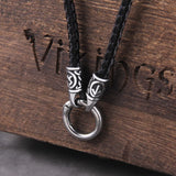 Silver pendant with black cord on a wooden surface with 'Vikings' branding.