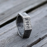 Silver ring with engraved text on a wooden surface