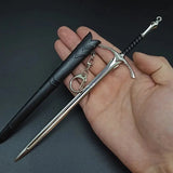 Hand holding a black pen and silver sword keychain against a dark background
