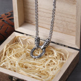 Silver necklace with intricate rune design in a wooden box