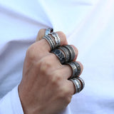 Hand wearing multiple silver rings with a blurred white background