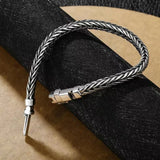 Silver braided bracelet with a clasp on a black sandal.