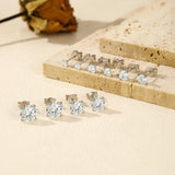 Silver stud earrings with clear gemstones on a beige surface