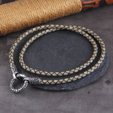 Braided leather necklace with metal clasp on a dark surface