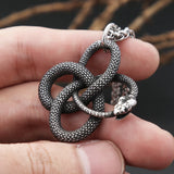 Silver snake-shaped pendant held in a hand against a blurred background