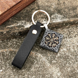 Silver and gold Keyring pendant   Keychain with black leather strap and geometric design on a textured surface