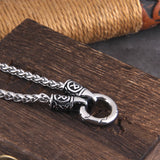 Silver chain necklace with intricate design on a wooden surface