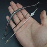 Hand holding a decorative bow and arrow against a dark background