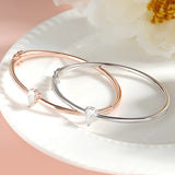Two gold , silver bangles with diamond stones on a white plate with flowers in the background
