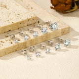 Silver stud earrings with clear gemstones on a beige surface