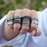 Hand wearing multiple silver rings with intricate designs against a blurred natural background