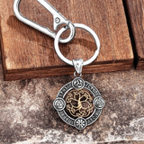 Silver keychain with intricate design on a wooden surface, featuring the brand 'Supretu'.