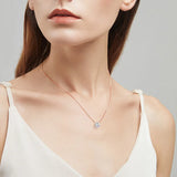 Woman wearing a delicate necklace with a clear pendant on a neutral background