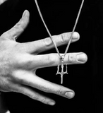 Hand holding a necklace with a pendant against a black background