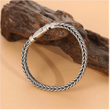 Silver braided bracelet on a wooden surface
