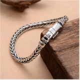 Silver braided bracelet on a wooden surface