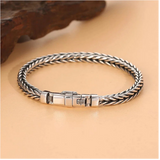 Silver braided bracelet on a beige surface